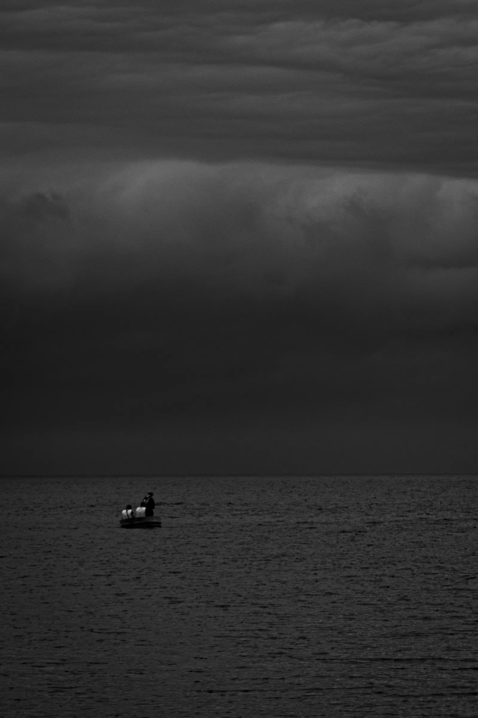 A very small boat beneath an immense dark sky