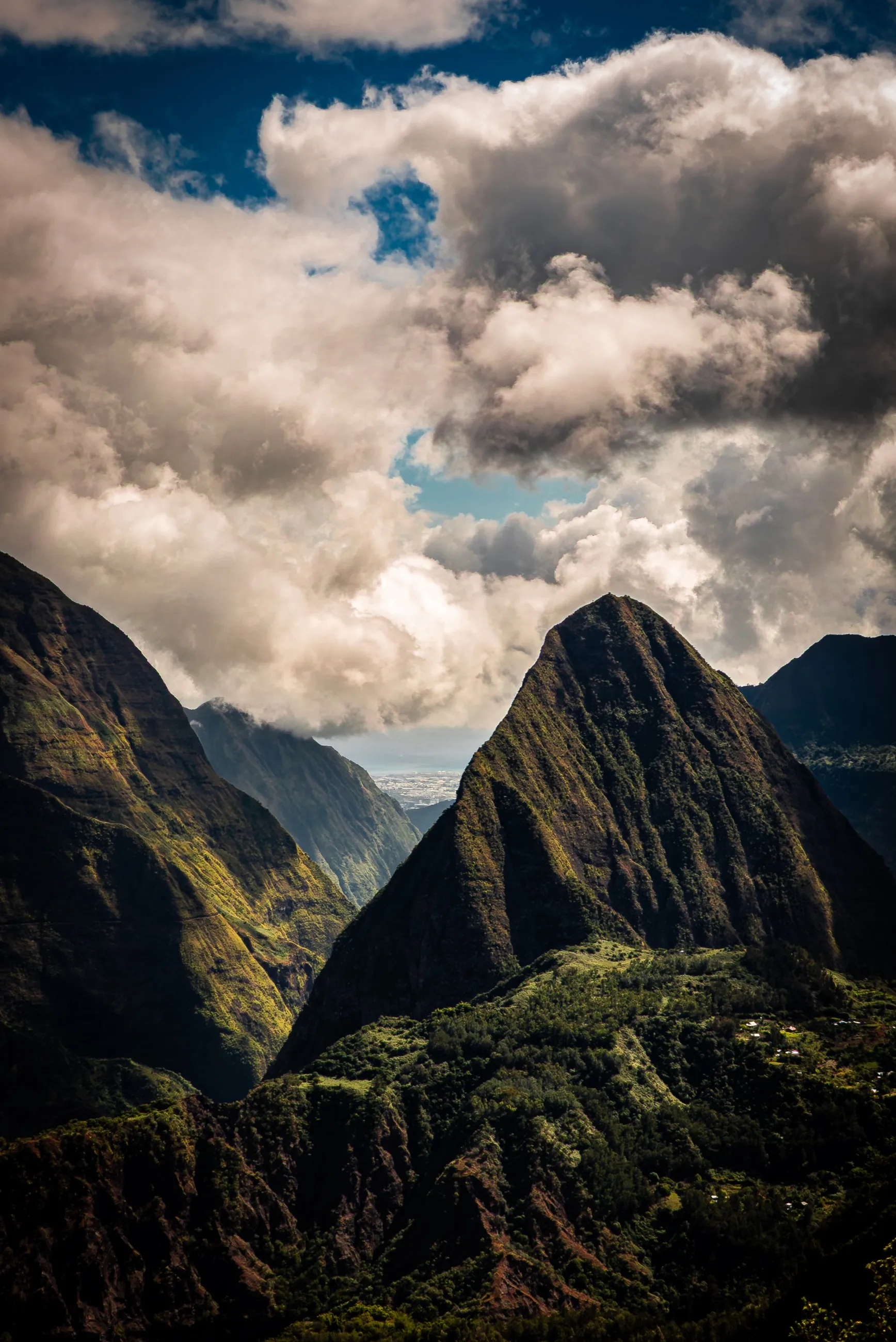Deep green ridges beneath a gathering field of clouds