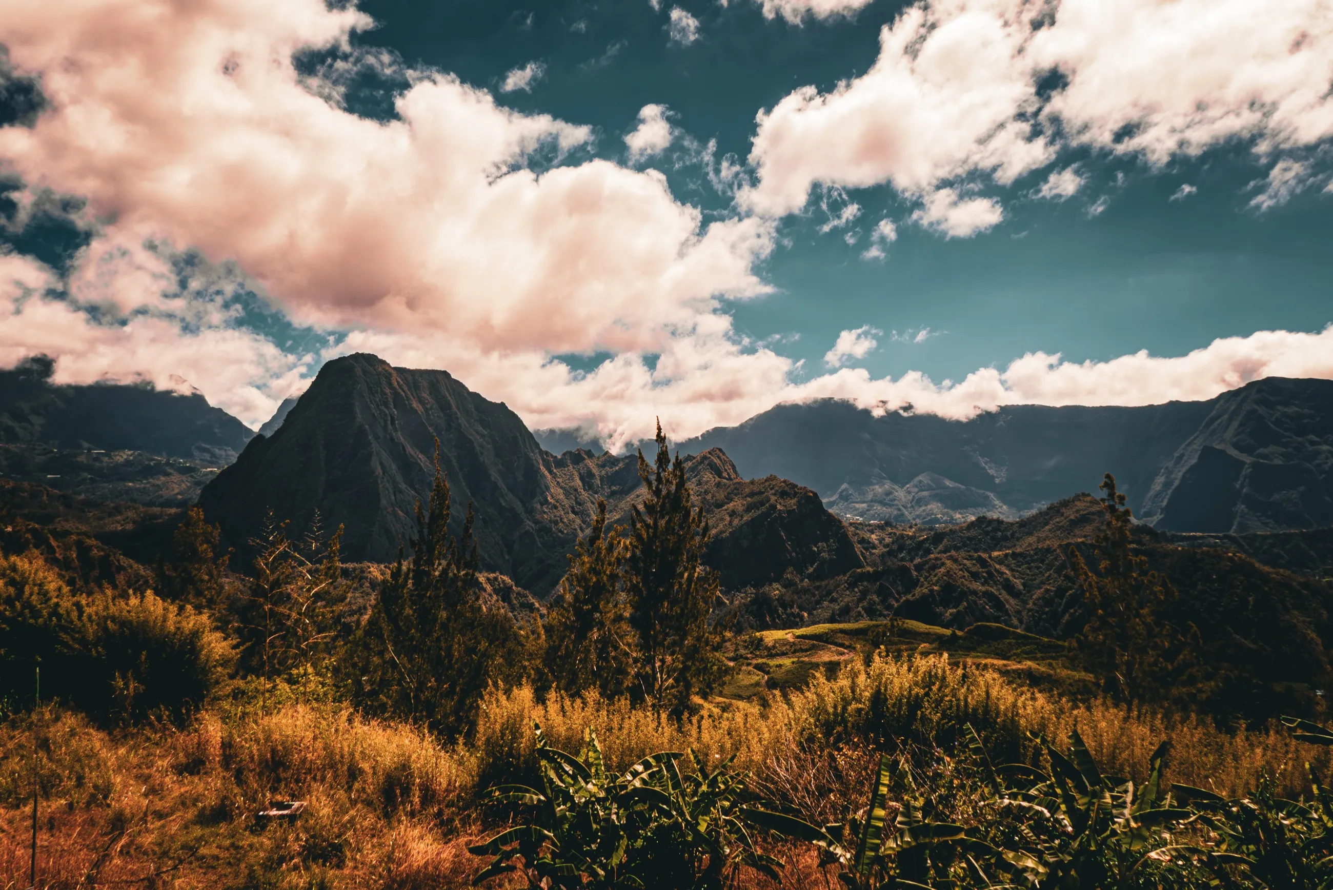Volcanic ridges rising beneath immense sunlit clouds