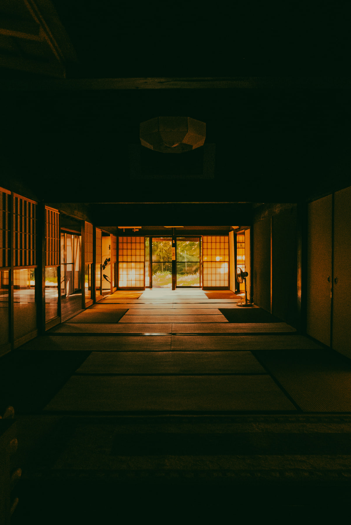 A long tatami corridor runs between sliding doors towards daylight at the far end.