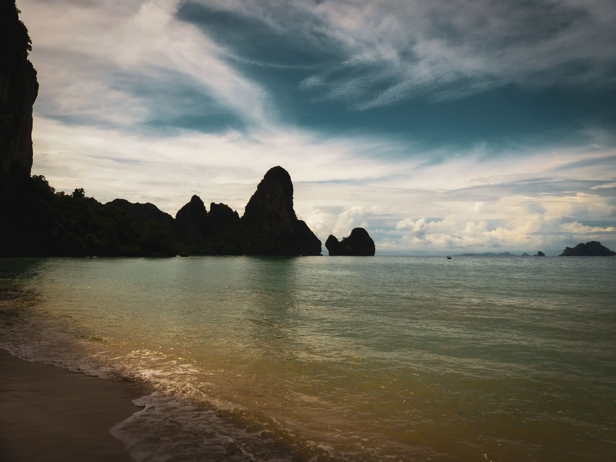 Limestone cliffs standing over a calm bay beneath heavy cloud.