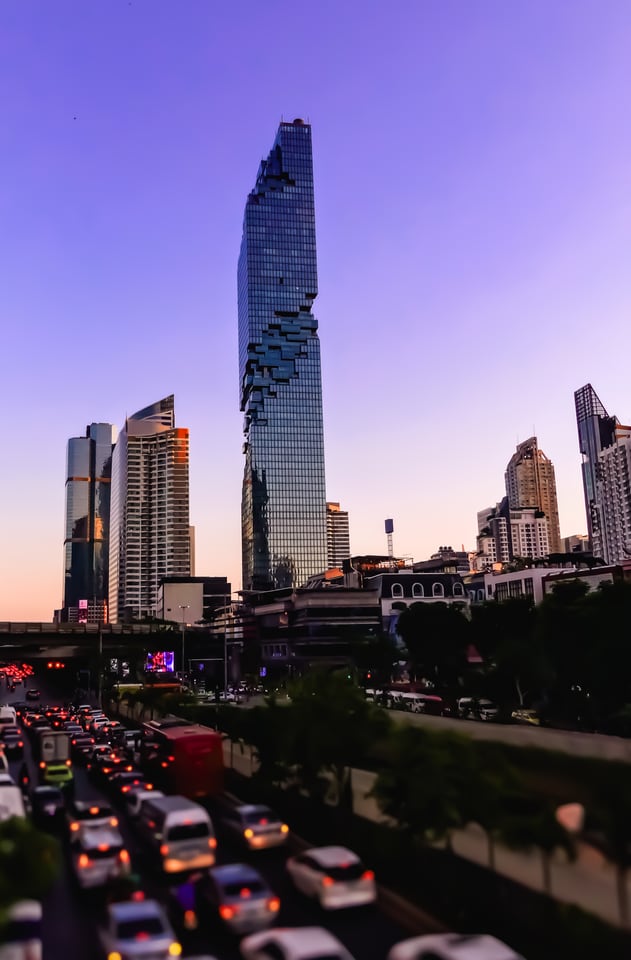 A twisted glass tower stands above lines of evening traffic.