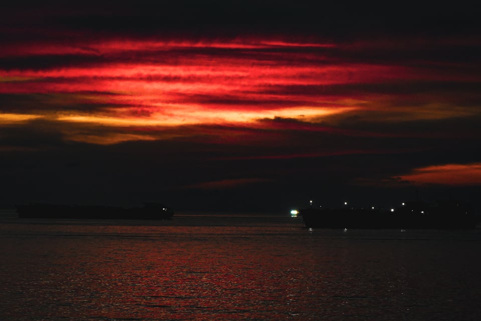 Red cloud burns above a dark sea at dusk.
