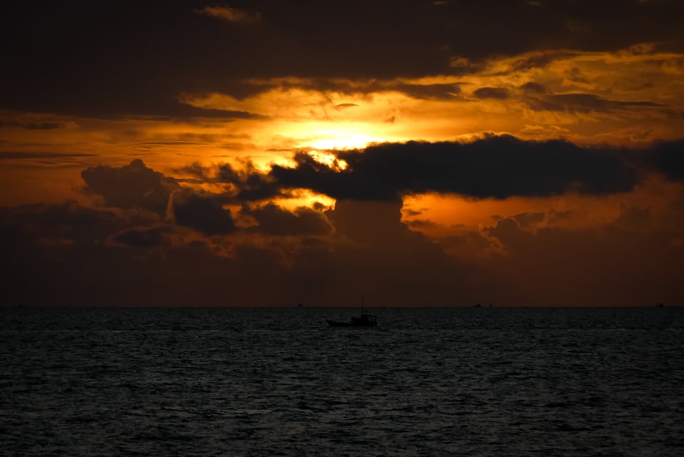 Sun breaks through cloud above a dark sea.