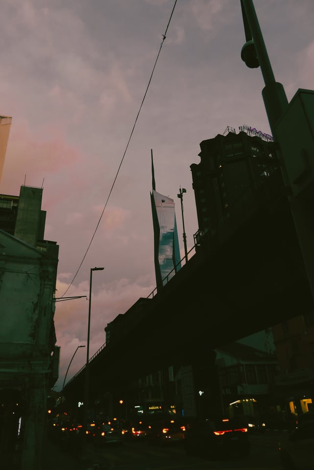 Traffic passes below an elevated road at dusk.