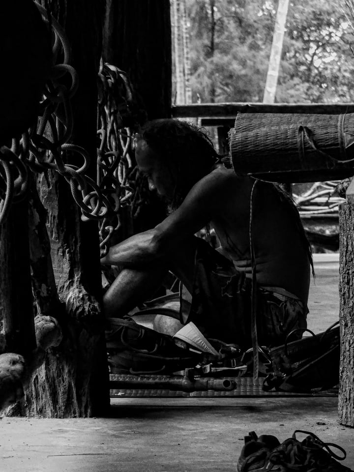 A seated craftsperson works beside a window.