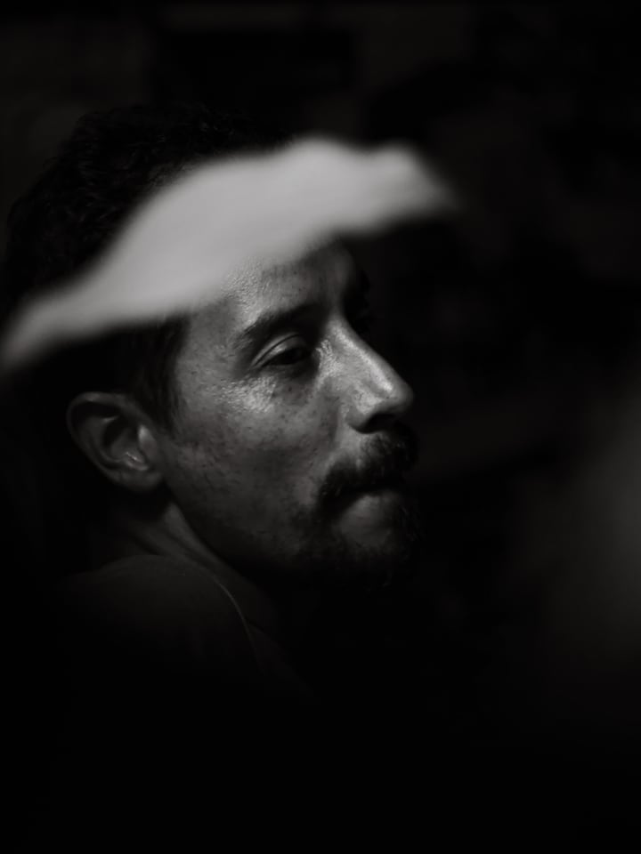 A man in a headscarf turns his face toward the light.