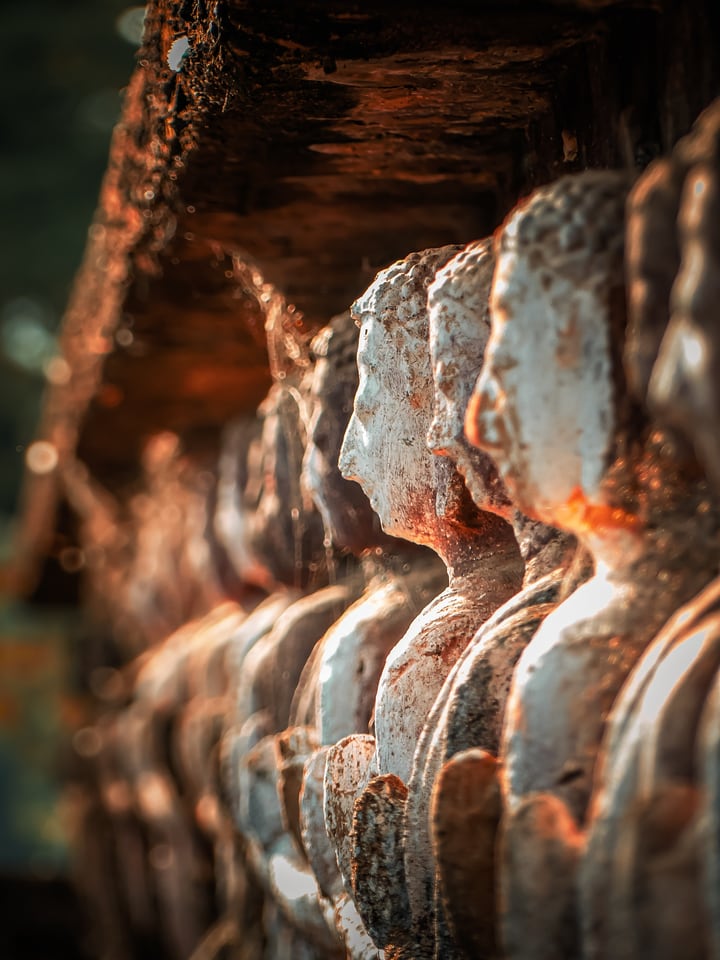 A row of weathered stone figures curves away in warm light.