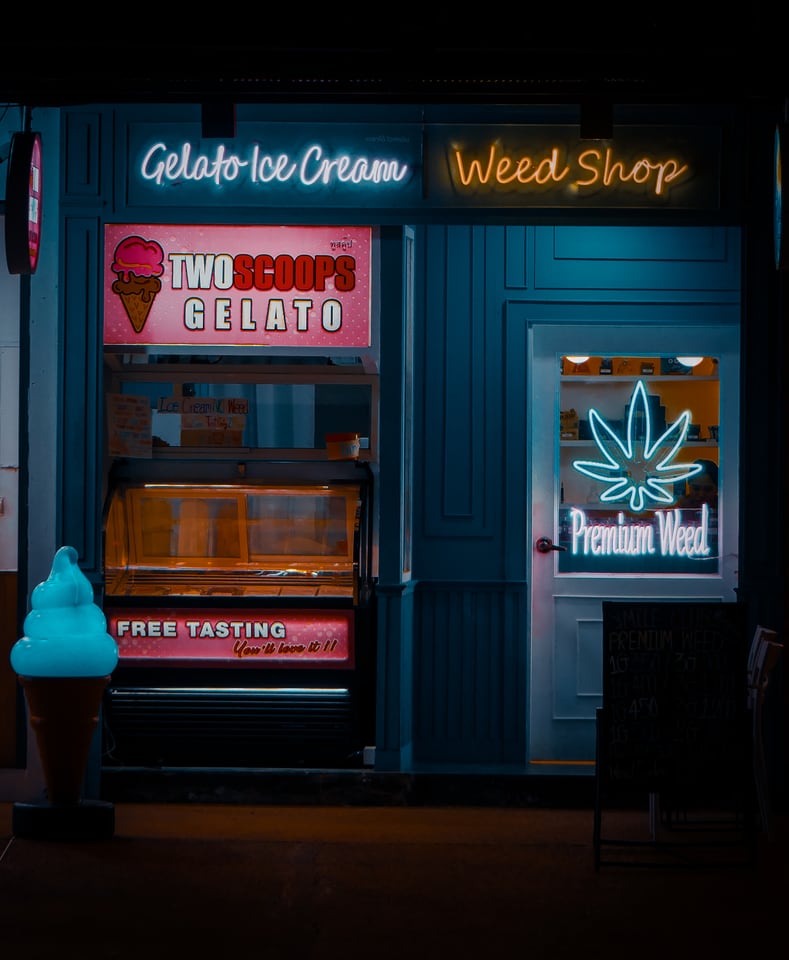 A gelato counter and a neon-lit shop door stand side by side at night.