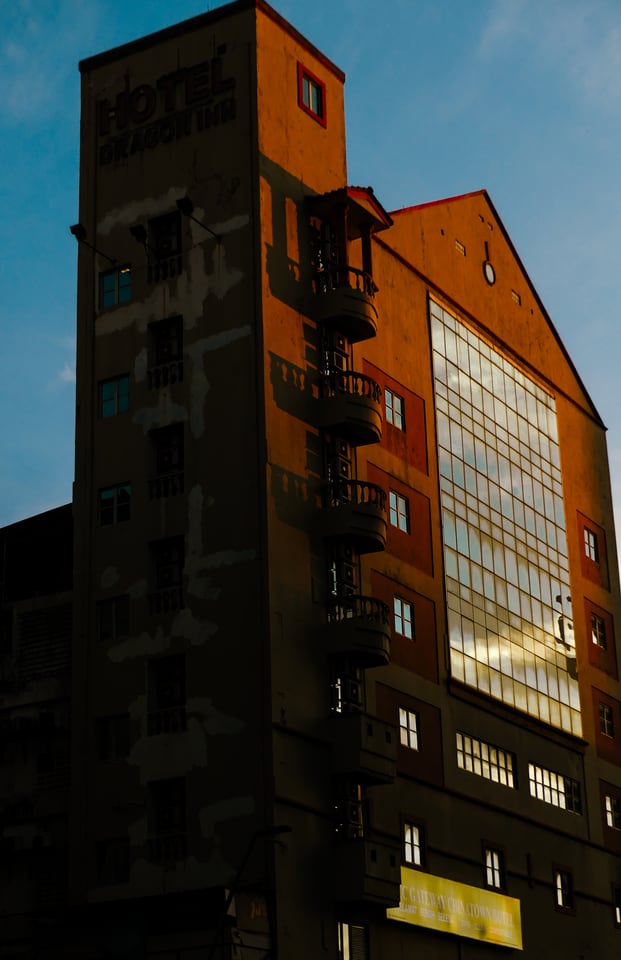 A tall hotel building stands against blue sky in low sun.