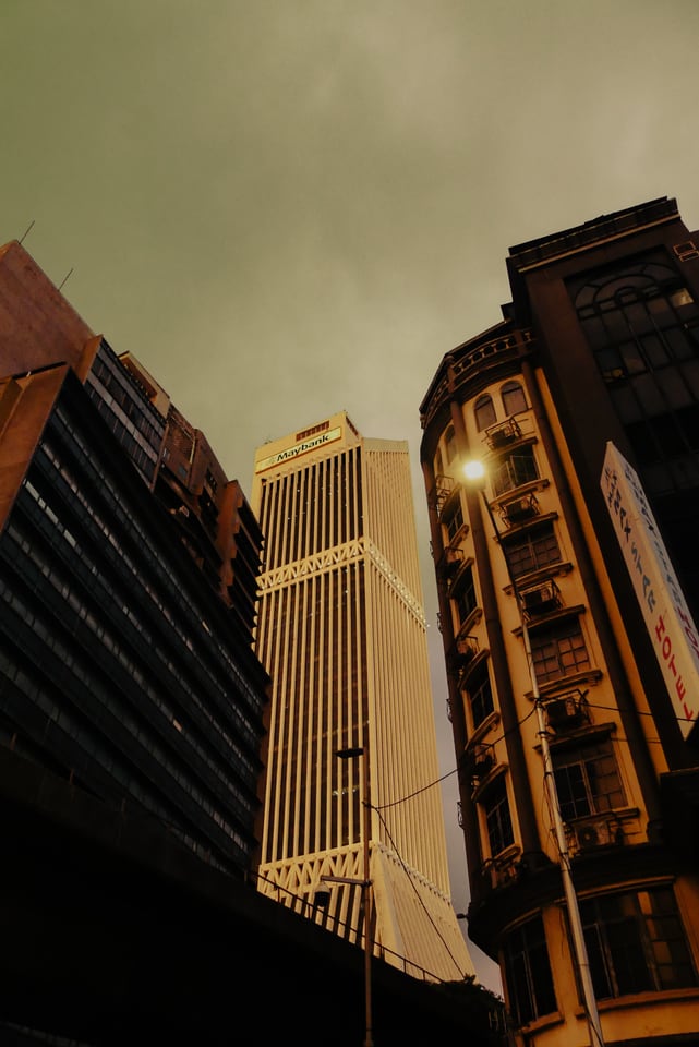 Towers and old shophouses crowd together, seen from below.
