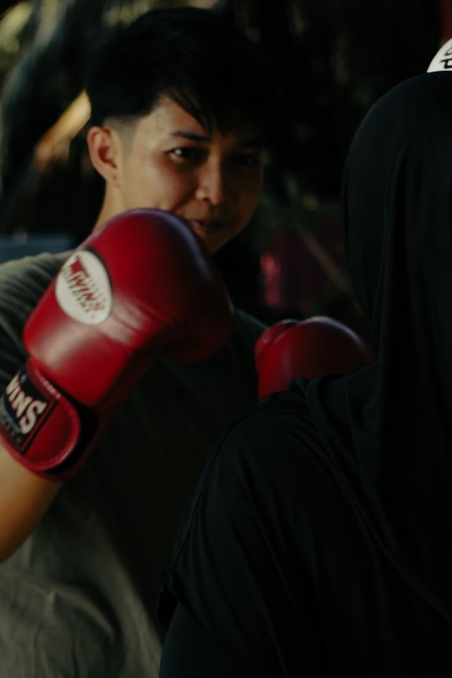 A person in red boxing gloves holds a guard in low light.