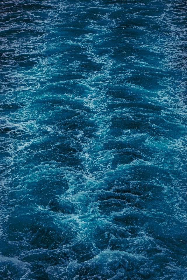Turquoise water churns across the whole frame in a ship's wake.