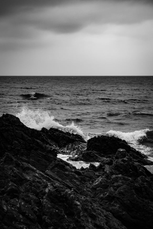 Waves break white over dark rocks below a low horizon.