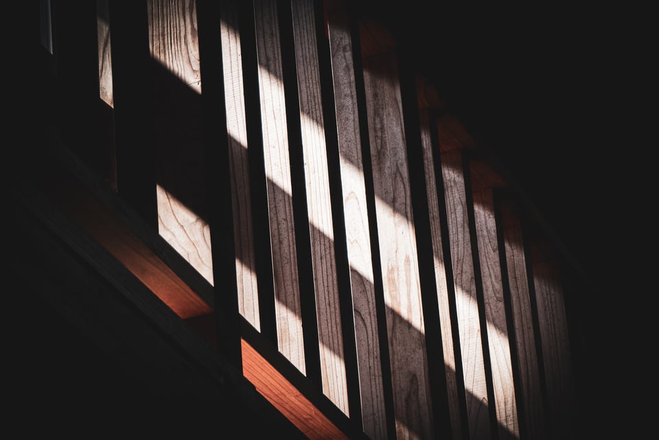 Bands of warm light fall through a dark wooden interior.