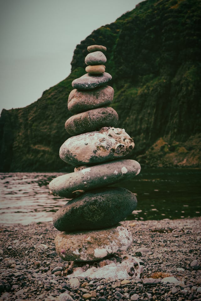 A stack of balanced stones on a shore of pale boulders.