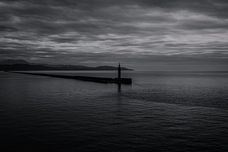 A breakwater lighthouse beneath a long grey sky.