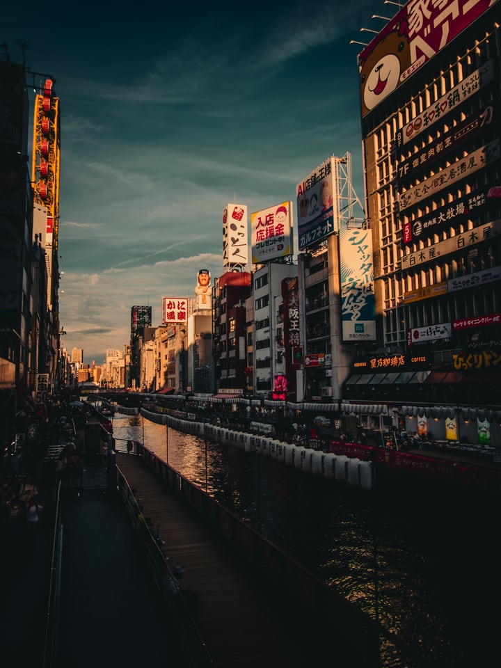 Signboards line both banks of a canal running into the evening city.