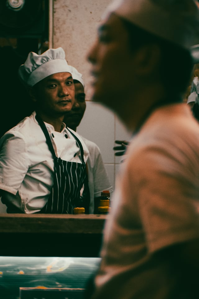 Two cooks in whites work behind a counter.