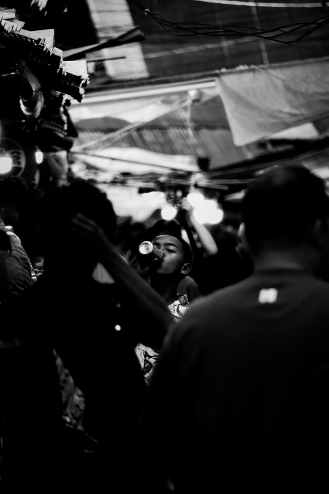 A child drinks from a bottle in a crowded night market.