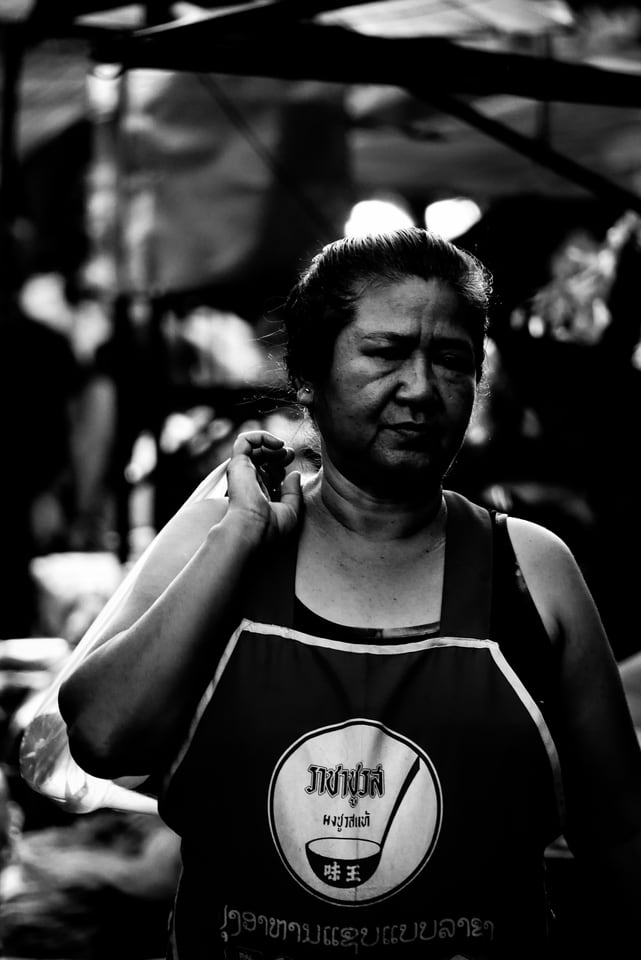 A woman in an apron stands at her market stall.