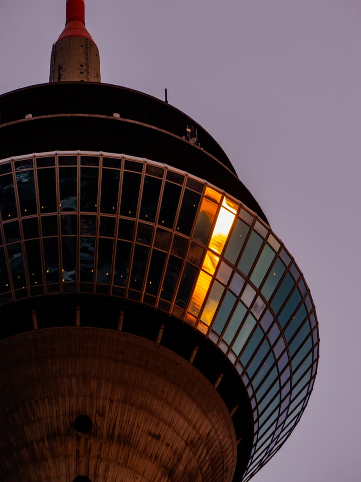 A single lit window in the observation deck of a tower at dusk.