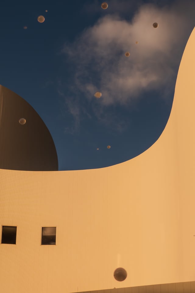 A pale curved wall cuts a long arc across cloud.