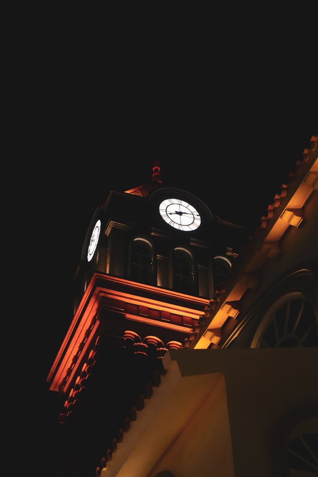 A lit clock tower stands against a dark sky.